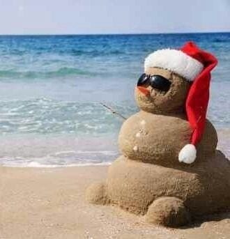 Sandman on the beach with shades and Santa hat.