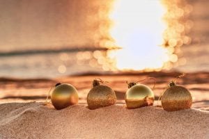 Gold ornaments sit on the beach, decorating the sands against the background sunset to commerate a Florida Gulf Coast holiday.