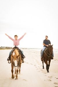 A girl raises her hand while enjoying a Cape Sans Blas horseback ride on the beach!
