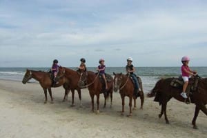 Group of riders on horseback on the beach.